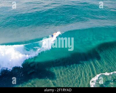 Luftaufnahme der Surfer warten, paddeln und genießen Wellen in einem schönen blauen Wasser Stockfoto