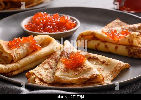 Russische dünne Pfannkuchen mit rotem Kaviar auf grau. Traditionelle Religion Frühstück für nationale Feiertag Fasching. Maslenitsa. Nahaufnahme. Stockfoto