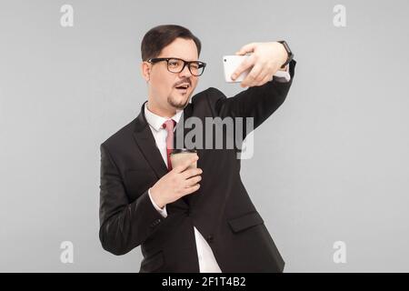 Business, Gadgets, Technologien. Mann macht Selfie. Indoor, Studioaufnahme, isoliert auf grauem Hintergrund Stockfoto