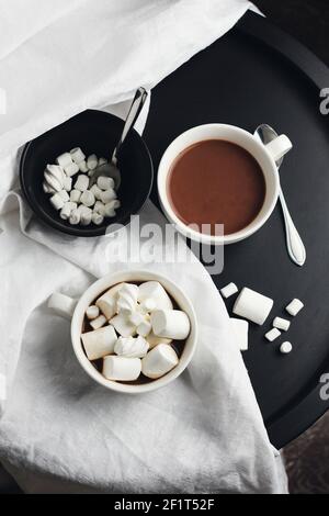 Zwei Tassen heiße Schokolade, Kakao mit Marshmallows auf einem runden Couchtisch. Stockfoto