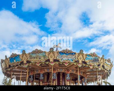 Fuengirola, Malaga, Spanien. Januar 2021. Detail eines traditionellen Kinder-Karussell unter einem blauen Himmel mit Wolken. Stockfoto