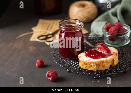 Himbeermarmelade im Glas und Sandwich mit frischen Himbeer-Beeren auf dem alten Retro-Hintergrund. Selektiver Fokus. Stockfoto