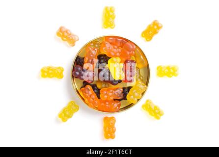 Gummibären in Form einer Sonne um eine Süßigkeitenkiste auf weißem Hintergrund angeordnet. Stockfoto