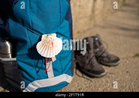 Nahaufnahme eines Muschelsymbols von Camino de Santiago auf Rucksack und Trekkingstiefeln. Pilgerfahrt nach Santiago de Compostela. Speicherplatz kopieren Stockfoto