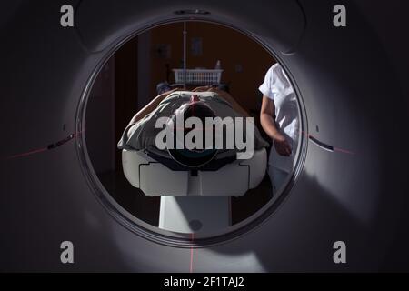 Leitender Mann, der in einem modernen Krankenhaus einen Computerized Axial Tomography (CAT) Scan medizinischen Test/Untersuchung durchläuft (farbiges Bild; flacher Freiheitsgrad) Stockfoto