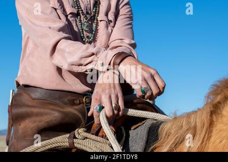 USA, Colorado, Custer County, Westcliffe, Music Meadows Ranch. Detail der weiblichen Ranchhand in typischer westlicher Ranchkleidung und türkisfarbenem Schmuck. Modus Stockfoto