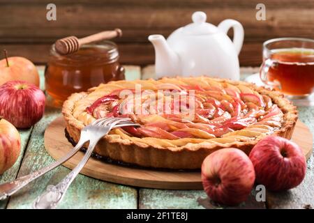 Köstlicher Apfelkuchen mit Bio-roten Äpfeln, Honig und Tee auf schäbigen blauen Hintergrund. Gesundes Apfeldessert Stockfoto
