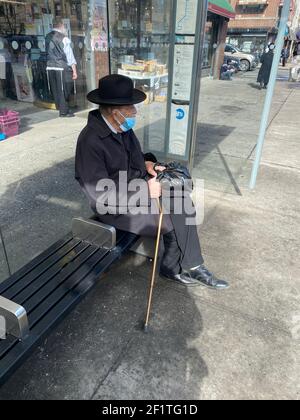 Ein älterer Mann wartet auf einen Bus entlang der 13th Avenue im Stadtteil Boro Park in Brooklyn, New York. Stockfoto