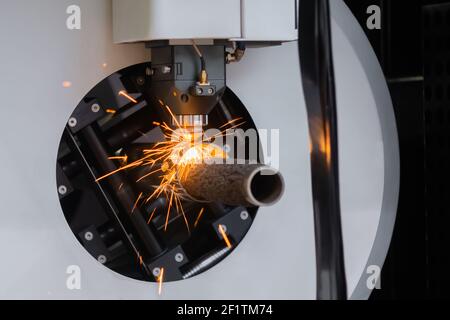 Laserschneidmaschine arbeitet mit zylindrischem Metallwerkstück mit Funken Stockfoto