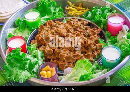 Roher Fleischbällchen-Tisch mit Buttermilch, Salat, Zitrone und Salat in Nahaufnahme Stockfoto