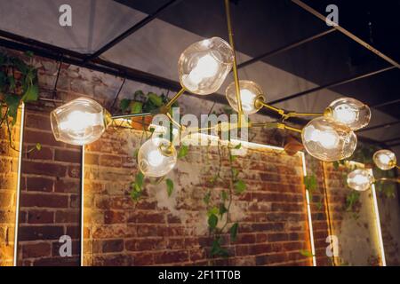 Viele runde Lampen in der Nähe einer braunen Holzwand. Runde Lichter im Innenraum. Hintergrund für Design. Dekorative Glühlampen Stockfoto