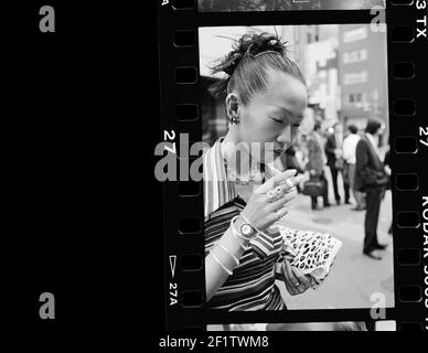 Junge japanische Mädchen Rauchen eine Zigarette abwesend gesinnt oder in einem verträumten Zustand auf der Straße, Tokio, Japan. Stockfoto