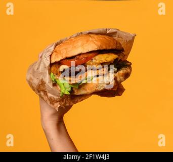 Frau Hände halten große Cheeseburger Grill Sandwich Burger mit Marmor Rinderkäse Tomaten Salat auf gelb orange Stockfoto