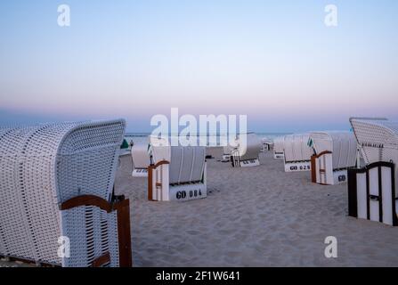 Ein wunderschöner Sonnenuntergang und Strandabend mit weißen Strandkörben Am Sandstrand Stockfoto