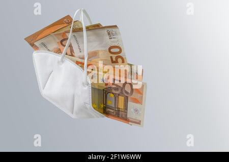 Medical FFP2 Gesichtsmaske gegen covid-19-Virus mit Euro-Banknoten gefüllt, Konzept zur Anreicherung durch Korruption oder steigende Kosten der Gesundheitsversorgung in pande Stockfoto