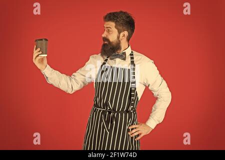 Brutale Kaffeemaschine. Porträt von bärtigen Barista stehen im Café. Barista gutaussehende Arbeiter. Freundliche Barista geben große Latte. Professionelle Kellner oder Barkeeper servieren Kaffee. Stockfoto