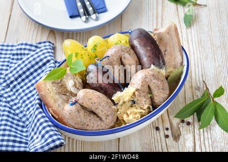 Bayerische Fleisch- und Wurstplatte mit frischem Schwarzpudding und Leberwurst, Schweinebauch, gekochten Kartoffeln und Sauerkraut Stockfoto