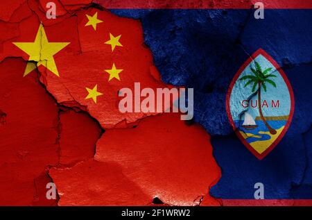 Flaggen von China und Guam auf rissige Wand gemalt Stockfoto