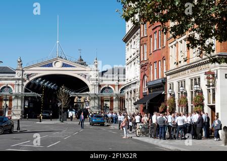 Die Leute trinken außerhalb Fullers Ale & Pie House Pub oder öffentlichen Haus mit Markt Gebäude im Hintergrund West Smithfield, London Stockfoto