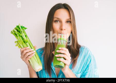 Gesunde Detox saubere Ernährung. Frau hält Sellerie und trinkt frischen Selleriesaft Stockfoto