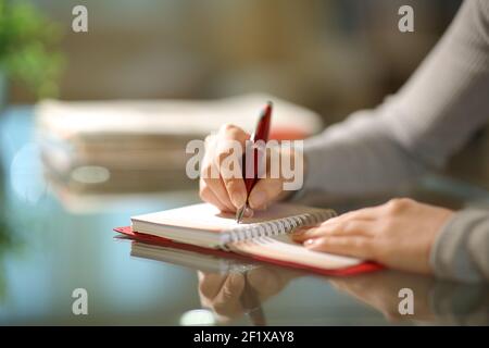 Nahaufnahme einer Frau Hände schreiben auf Papier Agenda In der Nacht zu Hause Stockfoto