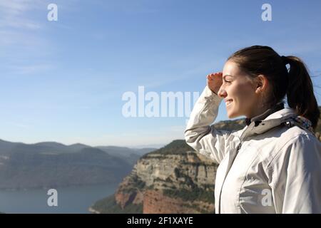 Seitenansicht Portrait eines glücklichen Trekkers mit dem man Ansichten nachdenkt Hand auf Stirn im Berg im Urlaub Stockfoto