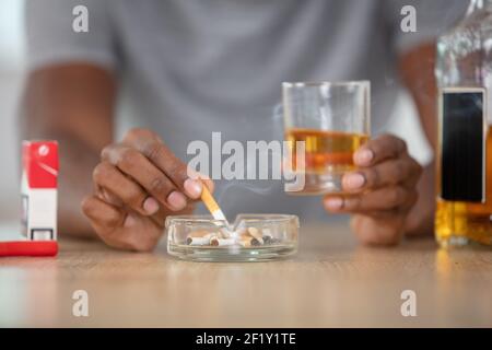 Verärgert jungen Mann trinkenden alkoholischen Rauchen Stockfoto