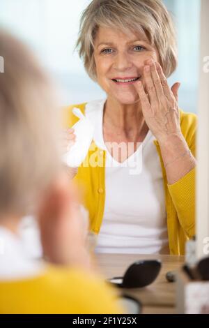 Schöne natürliche ältere Frau Anwendung nährende Gesichtscreme Stockfoto