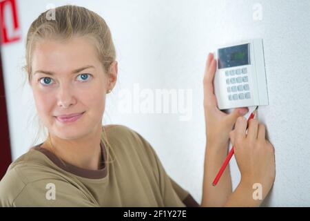 Junge Frau steuert zu Hause mit einem digitalen Touchscreen-Panel Stockfoto