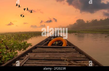 Landschaftlich schöner Sonnenuntergang am Fluss mit ländlicher Landschaft, von einem Fischerboot aus gesehen. Foto aus dem Burdwan Distrikt in Westbengalen, Indien Stockfoto