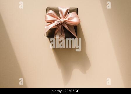 Geschenkbox auf beigem Hintergrund mit schattenförmigen Palmblättern. Minimalkonzept. Stockfoto