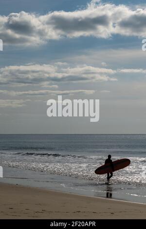 Surfer spaziert auf der französischen Cote in den Atlantik d'Argent, um einige Wellen zu fangen Stockfoto