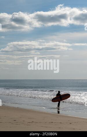 Surfer spaziert auf der französischen Cote in den Atlantik d'Argent, um einige Wellen zu fangen Stockfoto
