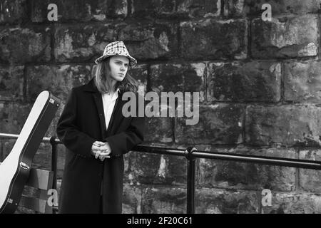 Schwarz-weißes Porträt eines Musikers, der neben einem Geländer steht und in die Zukunft blickt. Stockfoto