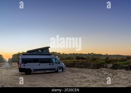 Camper van geparkt an einem idyllischen Zugang zum Strand bei Sonnenaufgang Stockfoto