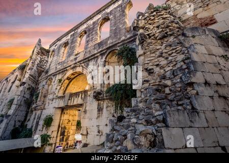 Eine Katze liegt bei Sonnenuntergang auf gestapelten Steinen in der Nähe des Silbertores des antiken Diokletianpalastes in der Altstadt von Split, Kroatien. Stockfoto