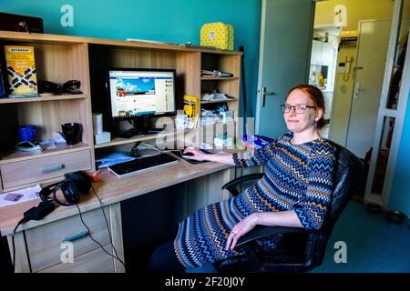 Roosendaal, Niederlande. Junge Frau, die zu Hause arbeitet und ihren Computer benutzt, um auf die Webseite des sozialen Netzwerks von Facebook zu zugreifen. Stockfoto