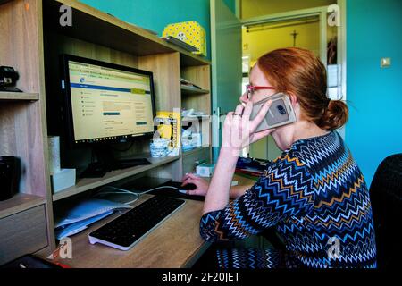 Roosendaal, Niederlande. Junge Frau, die von zu Hause aus arbeitet und ihren Computer und ihr Smartphone benutzt, um ihre Arbeitslosenunterstützung während der Krise in Corona/Covid-19 zu verwalten. Stockfoto