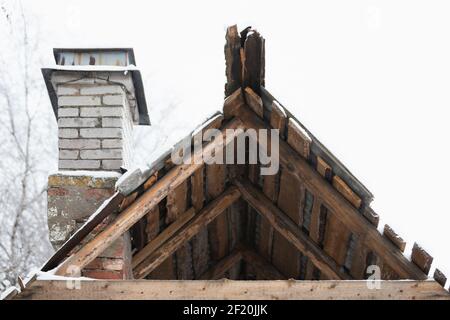 Altes verlassene Holzhaus Fragment, Dach und Kamin aus weißen Ziegeln Stockfoto