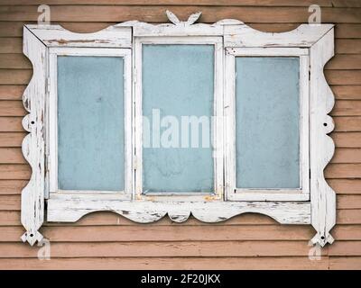 Gefrorenes Fenster in weißem dekorativen Rahmen, alte ländliche Holzhaus Wandfragment, Hintergrundtextur Stockfoto