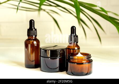Natürliches ätherisches Öl, Serum und Creme in braunen Glasflaschen auf einem Holzpodest. Alternative Medizin, aromatische pflanzliche Schönheit Hautpflege-Produkt Stockfoto