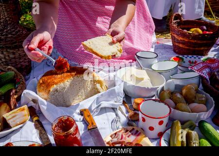 Traditionelle Mahlzeit, Frau schmiert Marmelade auf Brot, Frühstück in der offenen Zeit der Ernte. Stockfoto