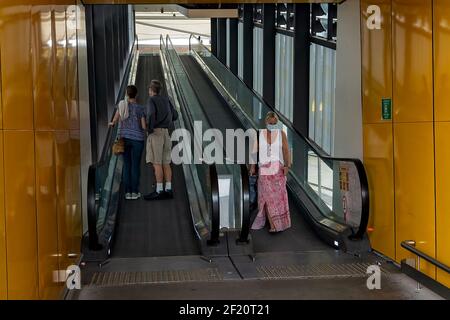 Brisbane Airport, Queensland, Australien - März 2021: Menschen mit Masken reisen während der Pandemie auf Rolltreppen Stockfoto