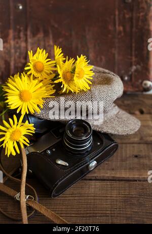 Nahaufnahme eines alten Kamera Vintage Hut und ein Strauß von gelben Blumen auf einem hölzernen Hintergrund Stockfoto