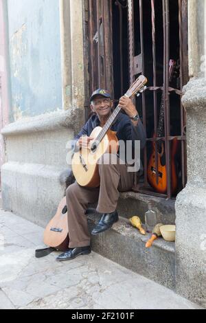 Kuba, Havanna - Mann spielt Gitarre auf seinem stoop, umgeben von Musikinstrumenten. Stockfoto
