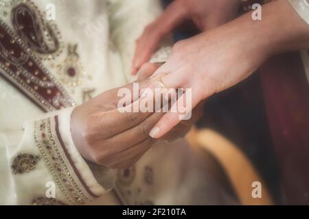 Indischer Bräutigam, der Ring auf eine Hand der Bräute legt Stockfoto