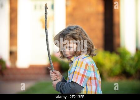 Unfreundlicher wütender Junge mit Stock. Mobbing Wut Konzept. Aggression von Kindern. Negative Emotionen für Kinder. Wütend Junge mit Stock. Kind Anpassung mit nervös Stockfoto