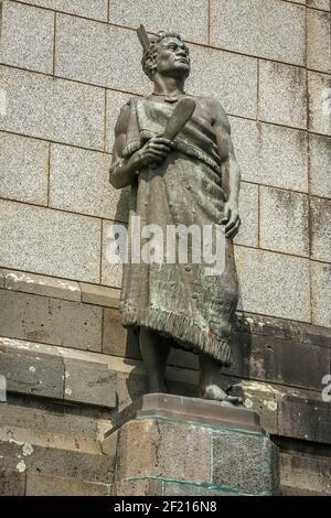 Eine Bronzestatue eines Maori-Kriegers, der einen Mantel trägt und einen bloßen (Club) auf einem Tree Hill, Auckland, Neuseeland trägt Stockfoto