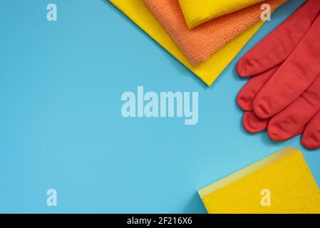 Hausreinigungszubehör: Schwamm, Gummihandschuhe und Tücher auf blauem Hintergrund. Draufsicht. Speicherplatz kopieren Stockfoto