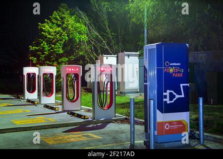 Eine Reihe von Ladestationen für Elektrofahrzeuge bei Nacht. Die meisten haben das Tesla-Logo. Taupo, Neuseeland Stockfoto